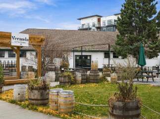 Discover Veranda at The Stables, a unique property offering a charming outdoor seating area adorned with rustic barrels and lush greenery.