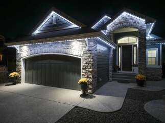 Illuminate your home with elegant exterior lighting, showcasing a beautifully crafted stone facade and a spacious garage.