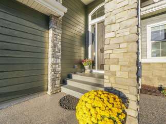 Welcome guests with this charming home featuring a covered porch and elegant stone accents.