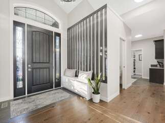 Step into a welcoming foyer featuring a grand arched entryway with a dark wood door and elegant stained-glass sidelights.
