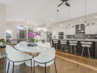This open-concept living space features a modern white marble dining table with elegant chairs, perfect for family gatherings.