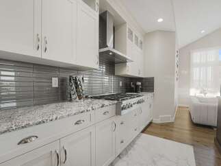 Experience modern elegance in this stunning kitchen, featuring sleek white cabinetry complemented by a sophisticated grey subway tile backsplash.