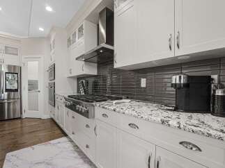 Experience luxury in this modern kitchen, featuring sleek white cabinetry and a stunning granite countertop.