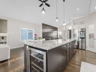 Experience luxury in this modern kitchen featuring a spacious island with a built-in wine cooler and granite countertops.
