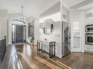 Step into a bright and airy foyer featuring a grand dark wood front door with arched glass transoms and sidelights.
