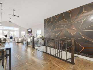 Experience modern living in this spacious open-concept home, featuring a vaulted ceiling with ceiling fans and abundant natural light from large windows and glass doors.