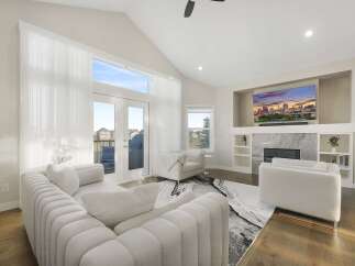 Experience modern luxury in this spacious living room, featuring a vaulted ceiling and abundant natural light from large windows and glass doors.