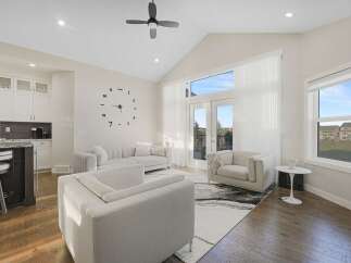Step into this bright and airy living room, featuring a vaulted ceiling and a large wall clock that adds a unique focal point.