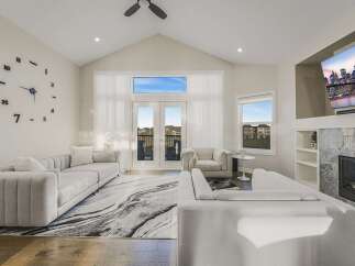 Experience luxury living in this stunning modern living room, featuring high vaulted ceilings and a dramatic floor-to-ceiling clock.