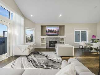 Experience modern living in this spacious open-concept living area, featuring a stunning fireplace and a large TV mounted above.