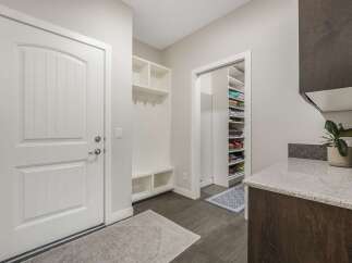 This spacious entryway features a white paneled door with a modern silver handle, leading into a well-organized mudroom.