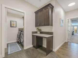 This spacious laundry room features a built-in dark wood cabinet and counter space, perfect for folding clothes or extra storage.