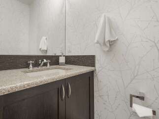 This modern bathroom features a sleek vanity with a granite countertop and a vessel sink, complemented by chrome fixtures.