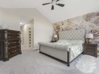 Experience luxury in this master bedroom, featuring a stunning tufted headboard and a dramatic floral wallpaper accent wall.
