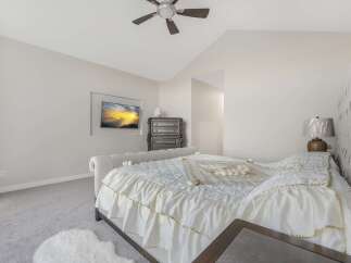 Experience luxurious comfort in this elegantly appointed bedroom, featuring a plush, white comforter with delicate gold trim and ruffled accents.
