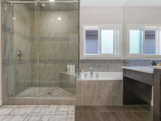 Experience luxury in this modern bathroom featuring a spacious glass-enclosed shower with pebble flooring and elegant mosaic tile accents.