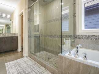 Experience luxury in this modern bathroom featuring a spacious glass-enclosed shower with pebble tile flooring and elegant mosaic tile accents.