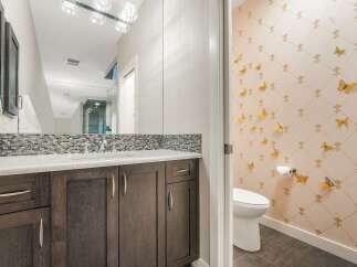 This modern bathroom features a dark wood vanity with a speckled countertop and a mosaic tile backsplash.