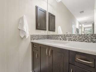 This modern bathroom features a sleek vanity with dark wood cabinetry and a white quartz countertop.
