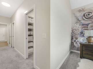Step into a beautifully appointed hallway featuring plush grey carpeting and a convenient linen closet stocked with neatly folded towels.