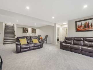 This spacious finished basement offers a comfortable living area with two large leather sofas and a wet bar.