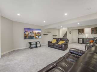 This finished basement offers a spacious entertainment area with a large flat-screen TV mounted above a sleek media console.