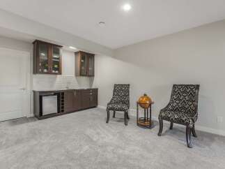 This basement features a stylish wet bar with dark wood cabinetry, a mini-fridge, and a wine rack, perfect for entertaining.