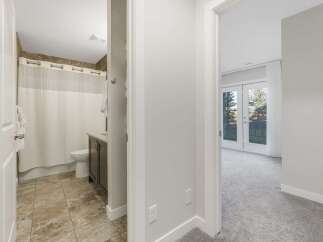 Step into a well-appointed bathroom featuring a tiled floor, a dark wood vanity, and a white shower curtain.