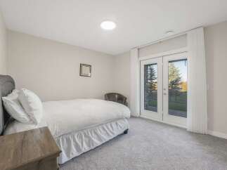 This bedroom offers a comfortable and serene retreat, featuring a plush bed with a textured duvet and a dark upholstered headboard.