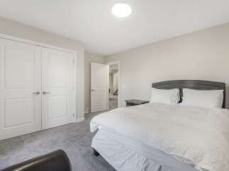 Step into this inviting bedroom, featuring a plush queen-size bed with crisp white linens and a stylish gray headboard.