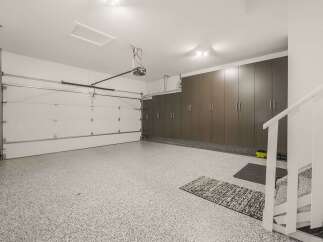 This spacious garage features a clean, modern aesthetic with a durable speckled epoxy floor and ample storage.