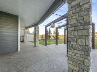 Enjoy outdoor living with this spacious covered patio, featuring a durable stone pillar and a modern gray siding exterior.