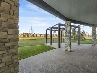 Enjoy outdoor living with this spacious covered patio, featuring a modern pergola and elegant stone pillars.