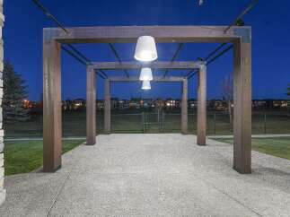 Experience the charm of this property's outdoor living space, featuring a modern pergola illuminated by stylish pendant lights.
