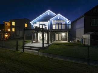 Experience luxury living in this stunning home, beautifully illuminated by festive lights against the night sky.