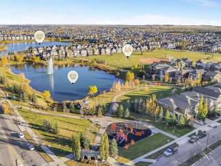 Discover this stunning aerial view of a family-friendly neighborhood, showcasing a serene lake with a fountain, a vibrant playground, and a baseball field.