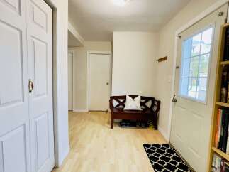 Welcome to this charming entryway, featuring a convenient bench with storage for shoes and a decorative pillow.