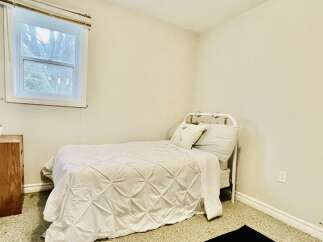 This cozy bedroom features a charming white metal bed with a plush duvet and decorative pillows, perfect for a restful night's sleep.