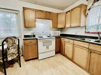This charming kitchen features light oak cabinetry and a white electric range, perfect for home chefs.