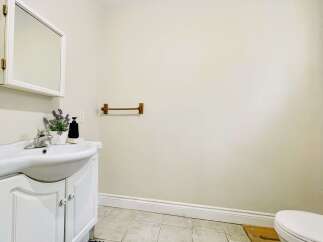 This charming bathroom features a white vanity with a curved sink and elegant cabinet doors, complemented by a mirrored medicine cabinet above.
