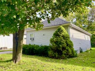 Charming single-family home featuring a light gray vinyl exterior and a dark gray shingled roof.