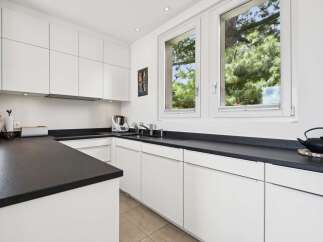 This modern kitchen boasts sleek white cabinetry and dark countertops, offering a sophisticated and functional space.