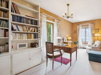 This elegant home office features a large built-in bookshelf filled with a diverse collection of books, creating a warm and intellectual atmosphere.