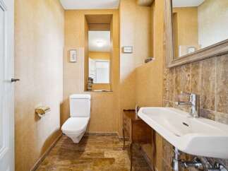 This charming bathroom features a classic white toilet and a sleek white sink, complemented by warm, textured yellow walls and a decorative tiled backsplash.