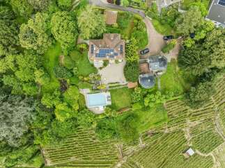 Discover this stunning aerial view of a luxurious estate featuring a main residence with solar panels, a separate guesthouse, and a private swimming pool.