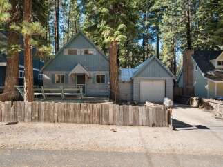 Nestled among tall pine trees, this charming blue cabin offers a rustic retreat.