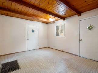 Discover the potential of this versatile room, featuring a charming wood-beamed ceiling and a practical linoleum floor.