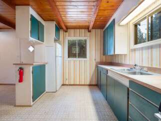 Step into this charming kitchen featuring rustic wooden beamed ceilings and vibrant striped wallpaper.