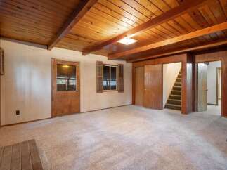 Step into this charming living space featuring a warm, wood-paneled ceiling with exposed beams, creating a cozy and rustic ambiance.