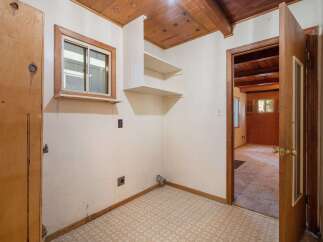 This interior shot showcases a functional laundry area with a small window and built-in shelving, perfect for storage.